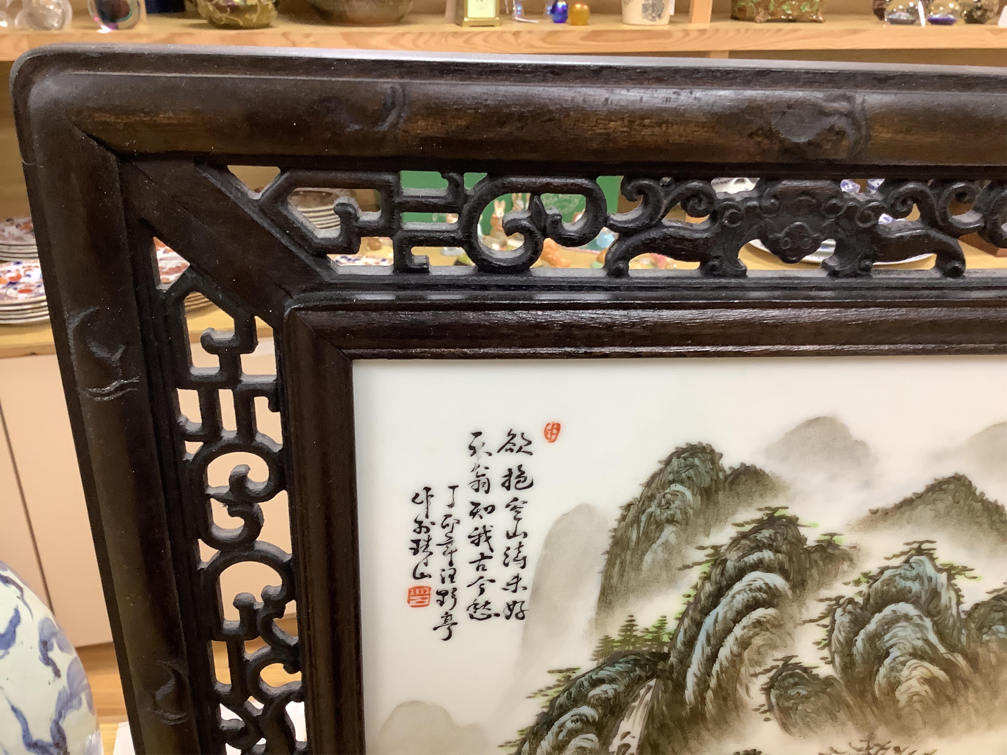 A Chinese carved wood table screen with a famille rose central plaque, screen 66cm high, plaque 35cm high. Condition - good